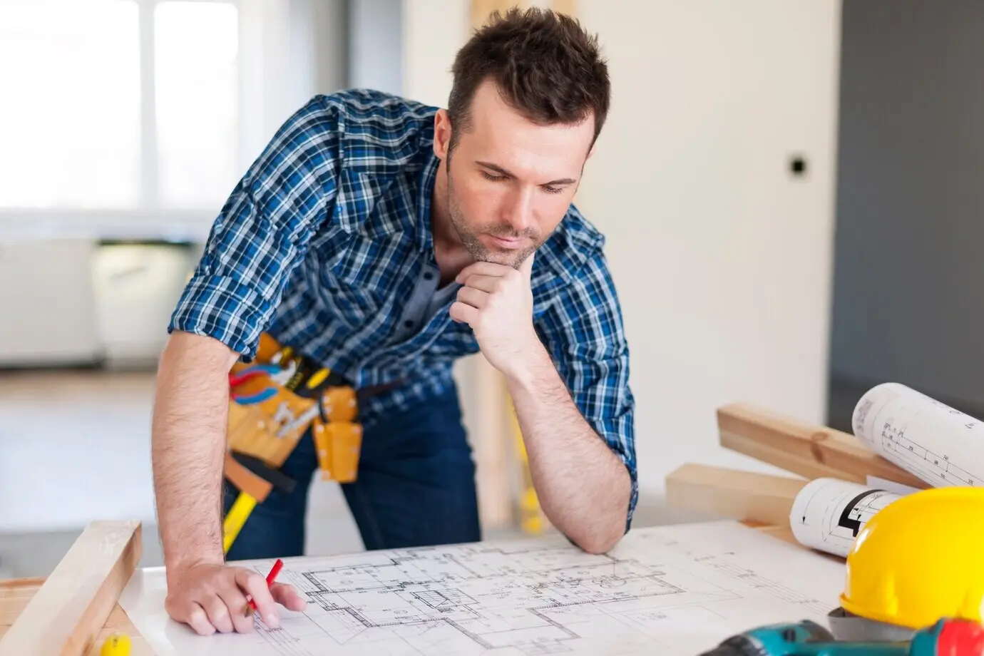 Building contractor leaning over home plans