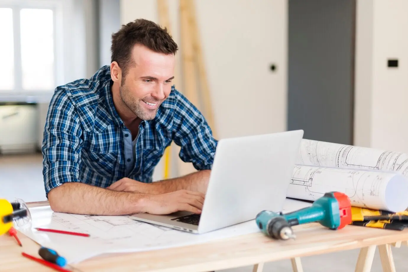 A smiling construction worker using a laptop.